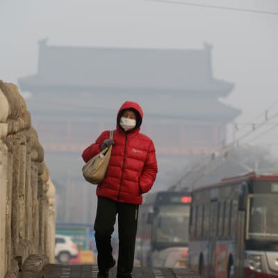 En kvinna går över en bro i Peking iklädd en ansiktsmask på grund av den förorenade luften.