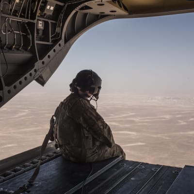 Yhdysvaltain merijalkaväen sotilas istuu helikopterin peräluukun reunalla ilmalennon aikana.