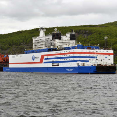 Den ryska kärnkraftsdrivna båten ligger vid hamnen. Båten är väldigt kubisk till sin design och är vit med blåa och röda streck.