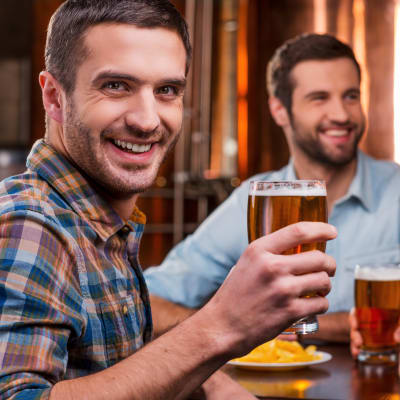 Män som dricker öl på en pub och skrattar. 