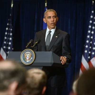 USA:s president Barack Obama bakom ett podium med USA:s och EU:s  flaggor i Bakgrunden. Obama fördömde dödsskjutningarna av poliser i Dallas under inledningen av Nato-toppmötet i Warszawa, Polen.
