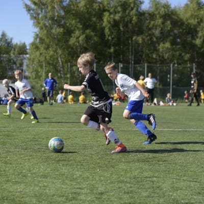 En spelare från SJK springer i kapp med en spelare från Kuffen under ett anfall under en fotbollsmatch.