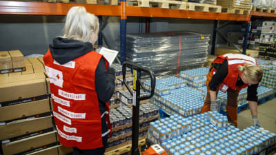Två frivilligarbete sorterar mathjälp i en lagerlokal i Tammerfors.