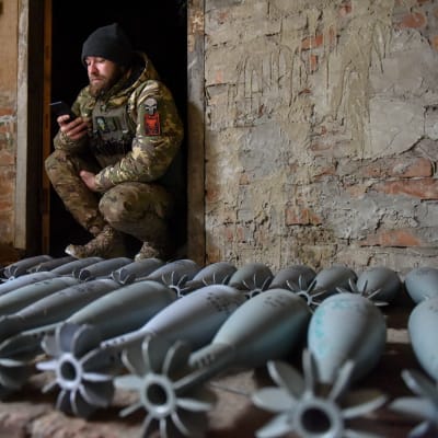Ukrainalainen sotilas katselee puhelintaan kranaatinheittimien ammuksia edessään käytettäväksi taisteluissa Donetskin alueella17. helmikuuta.