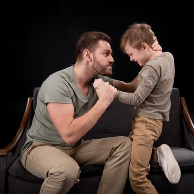 en pappa är arg och tar hårt i sin sons nacke och hand