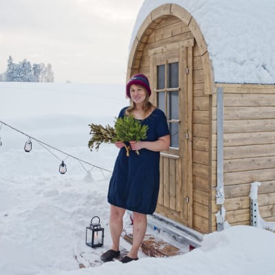 Sauna host and healer Laura Foon stands in front of her portable sauna on a snowy landscape.