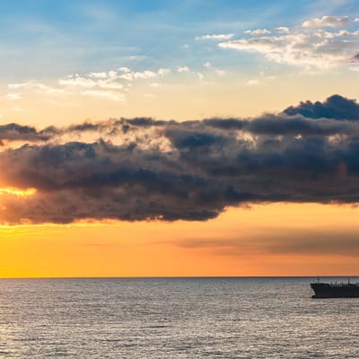En oljetanker på havet i solnedgång.