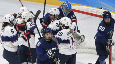 USA:s hockeydamer firar framför Finlands mål.