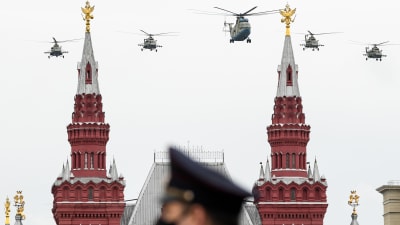 Militärhelikoptrar över Kreml under flyguppvisningen på segerdagen 9.5. En soldat i mask i förgrunden. 