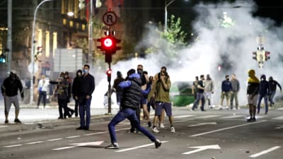 På bilden gata i Belgrad där demonstranter springer. De omges av rök.