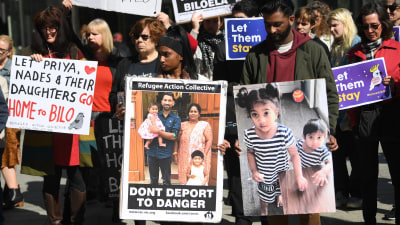 Demonstranter som håller upp plakat med bilder på familjen Murugappan.