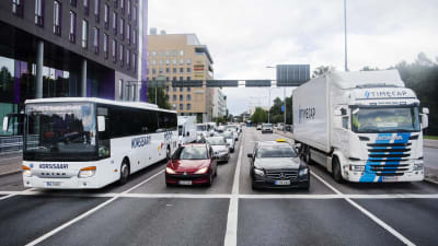 På bilden en buss, en personbil och en lastbil som kör längs Mannerheimvägen i Helsingfors. 