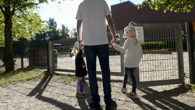 En förälder med sina två barn utanför ett daghem i Esbo.