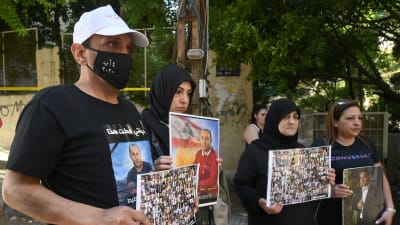 Personer som håller upp bilder på dem som dog i explosionen i Beirut 2020.