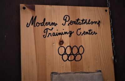 Skylt med texten Modern Pentathlon Training Center, som hänger på väggen hemma hos femkampsfamiljen Salminen.