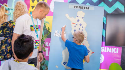 Toni Hellinen opastaa lasta säänennustamisessa.