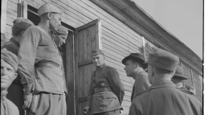 Män står utanför en dörr på det tyska fånglägret på Tulludden i Hangö.