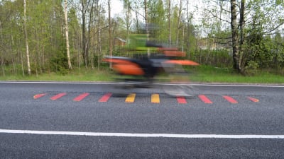 motorcykel kör över ett ingröpt trafikmärke i asfalten
