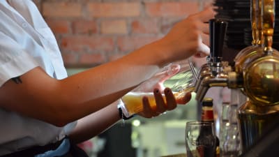 Barpersonal häller upp öl i ett glas från en ölkran.