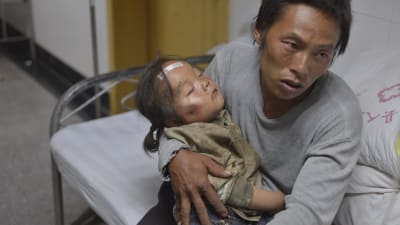 En far med barn väntar på vård i sjukhuset i Ludian i Yunnan-provinsen