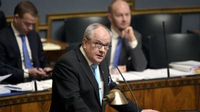 Riksdagsledamot Kaj Turunen talar, Petteri Orpo och Sampo Terho i bakgrunden.