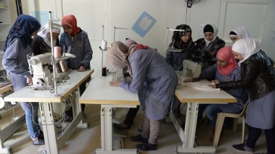 Syriska flyktingbarn står vid bord med symaskiner och deltar i en syslöjdsklassi östra Libanon.