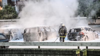 Brandmän har sprutat släckningspulver på en handfull bilar som fortfarande ryker efter brand.