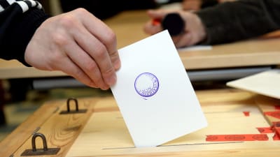 En person sätter röstsedeln i valurnan.