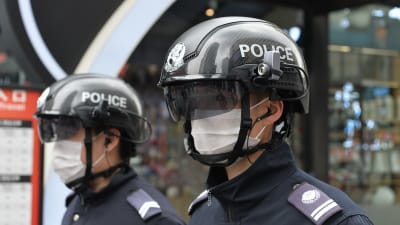 Två män i mörkblå polisuniform med hjälmar på huvudet med texten "POLICE". Hjälmarna har kameror och mörka visir.