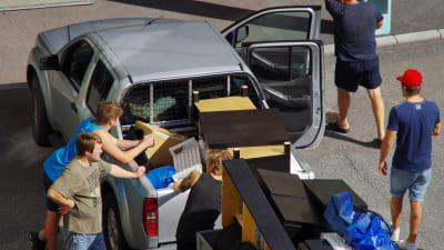 En grupp personer lastar möbler från en släpkärra.