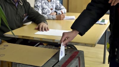 Person lägger röstsedel i låda