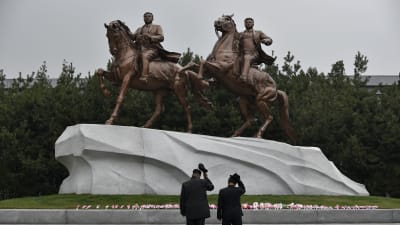 Två män visar sin respekt inför statyer av landsfadern Kim Il Sung och sonen och arvtagaren Kim Jong Il