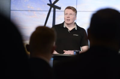 Myrsky energias grundare Tuomas Candelin-Palmqvist på en pressträff med bilder på vindmöllor bakom sig.