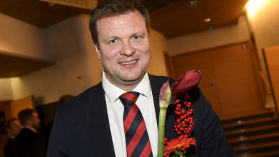 Ville Skinnari (SDP) ler mot kameran med blommor i händerna.