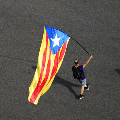 En man bär den katalanska flaggan under den autonoma regionen Kataloniens nationaldag den 11 september