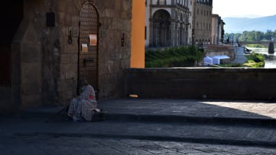 En kvinna sitter på trottoarkanten i ett ödsligt Florens