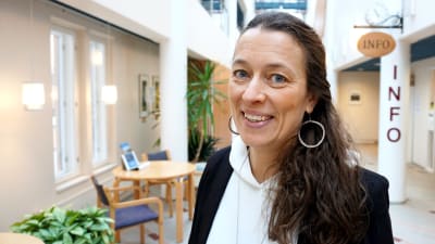 Kvinna i svart kavaj står i en korridor.