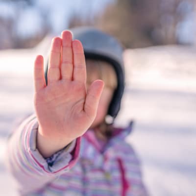 Flicka sätter ut handen som ett stoppmärke. 