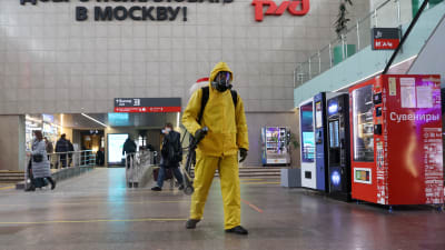 En man i skyddsutrustning desinficerar en tågstation i Moskva inför nyårstrafiken.
