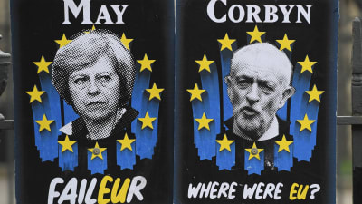 Affischer som förlöjliggar May och Corbyn utanför Houses of Parliament i Westminster. 