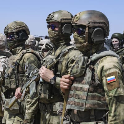 Soldater i utrustning står på rad. En av dem har en rysk flagga på armen.