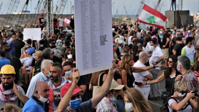 Demonstration och minnesstund i Beiruts hamn. En libanesisk demonstarant bär en skylt med namnen på de personer som dog efter explosionen i Beirut 4 augusti 2020.