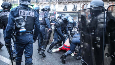 Polis samlade runt en demonstrant i Paris som ligger på marken.