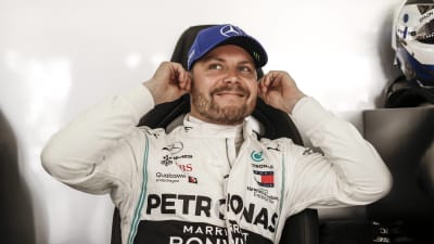 Valtteri Bottas håller sig vid öronen och ler mot kameran.