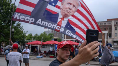 Trumpsupportrar viftar med en jätteflagga med presidentens bild.