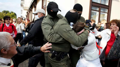 En polis håller fast en kvinna runt huvudet under en demonstration i Minsk den 12 september 2020.