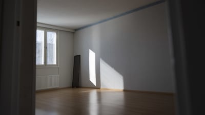 Solen tittar in genom ett fönster och skapar skuggor i en tom lägenhet.