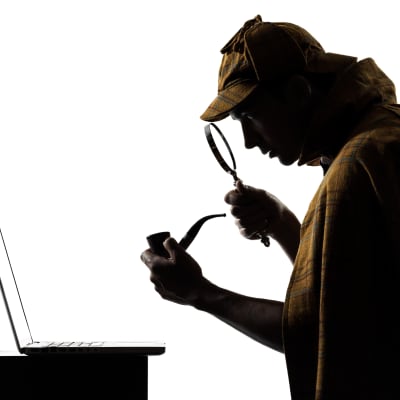 Sherlock Holmes -hahmo katsoo suurennuslasilla kannettavaa tietokonetta