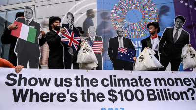 I mittenskiktet personer och kartongfigurer av människor. I förgrunden en text som frågar var 100 miljarder dollar av utlovade klimatpengar håller hus.