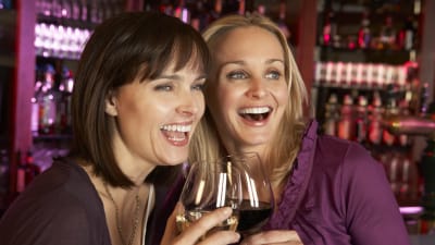 Två leende kvinnor dricker vin